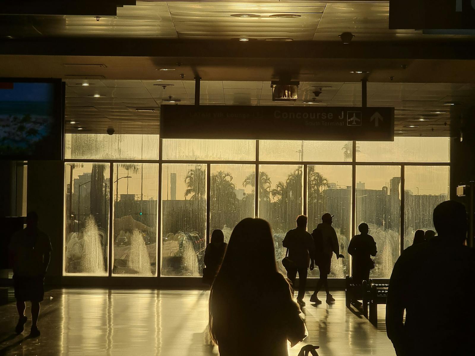 Sunlit Miami airport terminal with travelers in silhouette